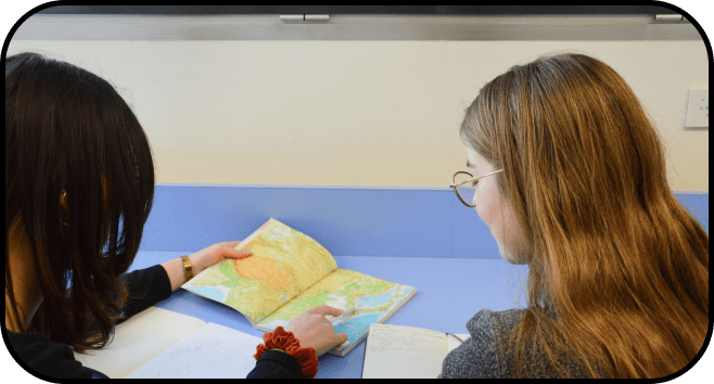 two girl students learning from a textbook